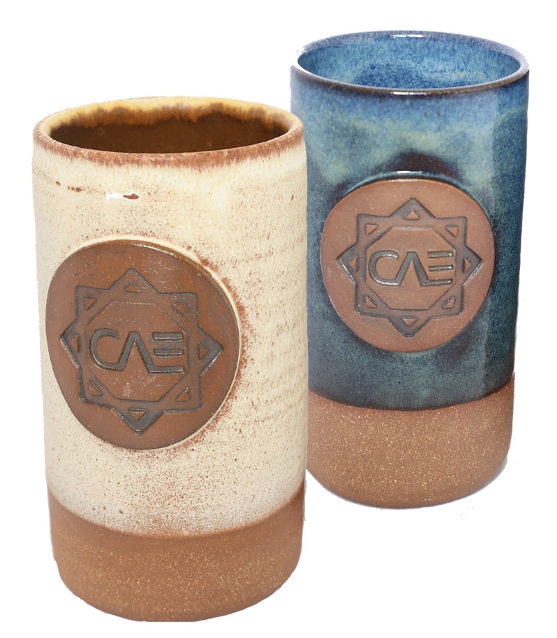 Product Description: CAE's Development Manager, Katrina Vahedi, is also a local potter! These tumblers were designed and fired in her studio and made by her and Silene Sutera (CAE Farm Business Advisor). The tumblers hold about 14 fluid ounces, and are glazed in a deep marine blue or an ivory matte, stopping to reveal the bare clay at the bottom of this cup. $50 for one tumbler.</br> CAE Tumbler